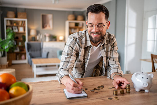 istock Man managing home finances and counting savings at home 2218966438