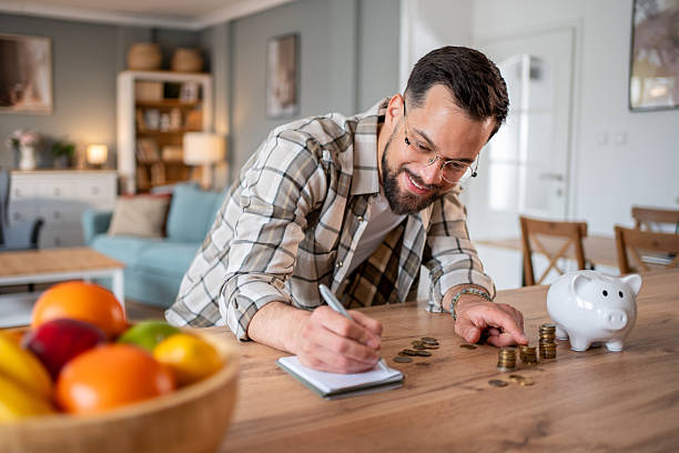 istock Smiling man counting coins and taking notes at home 2218966441