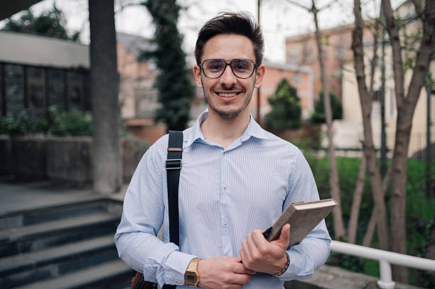 istock Smiling young adult student holding book outdoors near university campus 2218966621