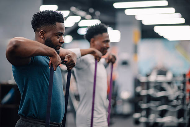 Two young men performing resistance band exercises in gym