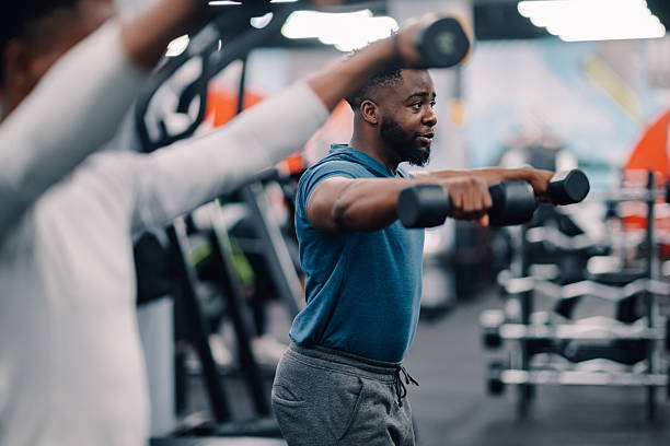 istock Determined black man lifting weights in gym with another person 2218966858
