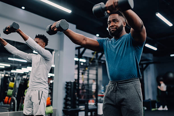 Two young men lifting weights during functional training in the gym
