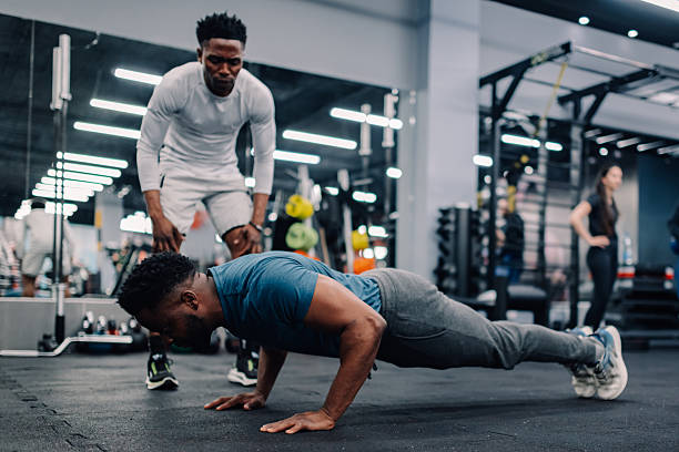 istock Determined male athlete doing push-ups with personal trainer in gym 2218966868