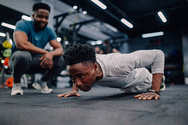 istock Determined young man doing push-ups with personal trainer in gym 2218966870