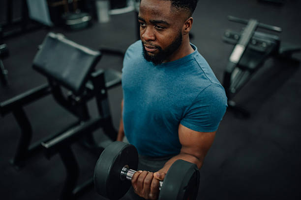 istock Young adult lifting weights concentrating during bicep curl exercise 2218966932