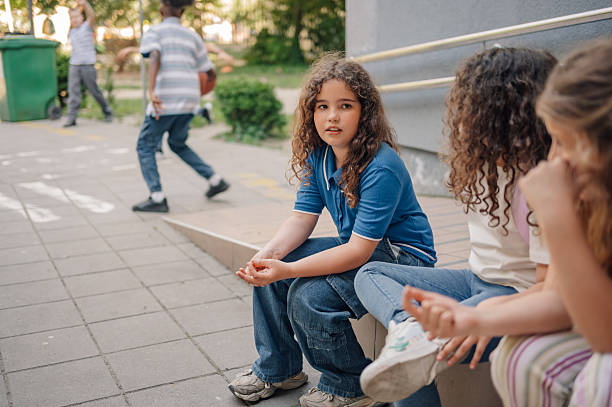 istock Schoolgirls chatting together while schoolboys playing basketball 2218967416