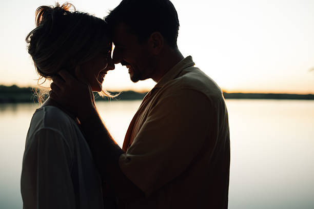 istock Romantic couple embracing at sunset by a lake 2218970461