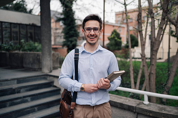 Smiling university student holding a book and a satchel