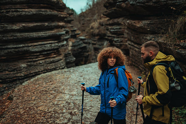 Young hikers with backpacks and trekking poles navigating a rocky canyon, surrounded by stunning rock formations and vibrant nature