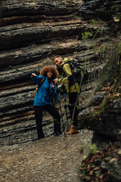istock Hikers exploring narrow gorge with hiking poles and backpacks 2218970703