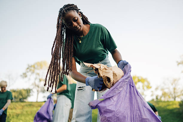 Young volunteer picking up trash in park during community cleanup
