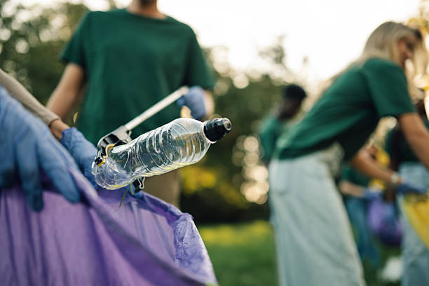 istock Volunteers picking up plastic bottle in park cleanup 2218970973
