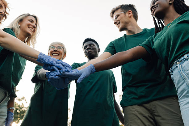 istock Group of volunteers joining hands wearing protective gloves 2218970994