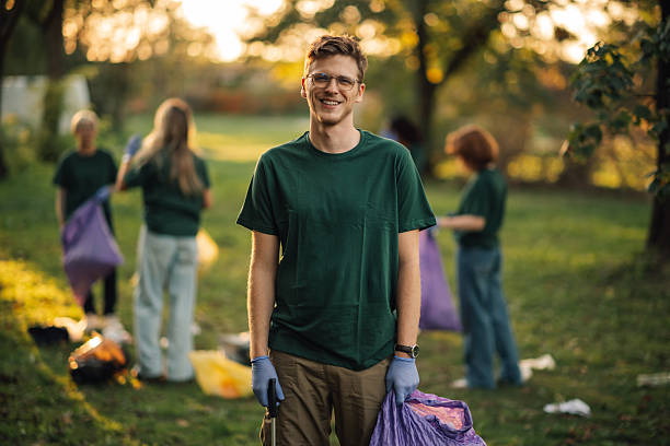 istock Young volunteer picking up trash in park during community cleanup event 2218971016