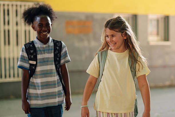 istock Two elementary school students smiling and walking in school hallway 2218971233