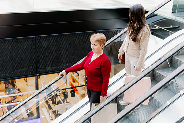 istock Two women walk down an escalator in a shopping mall. 2218977499