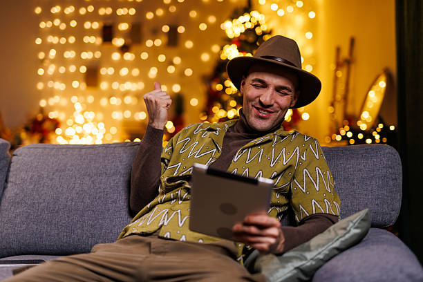 istock Man celebrating success on a tablet in a cozy festive home environment 2218978820
