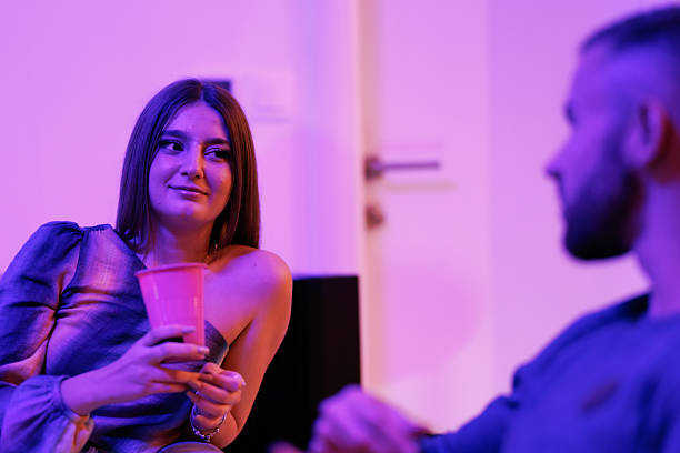 istock Two people interacting at an indoor gathering under warm violet lighting 2218978899