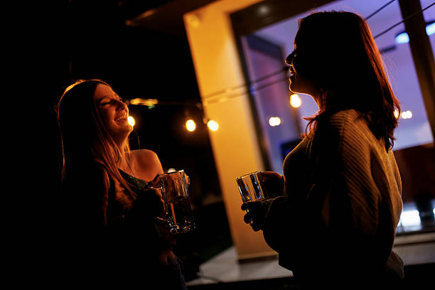 istock Two Friends Enjoying an Evening Together With Drinks Outdoors Around Warm Lighting 2218978954
