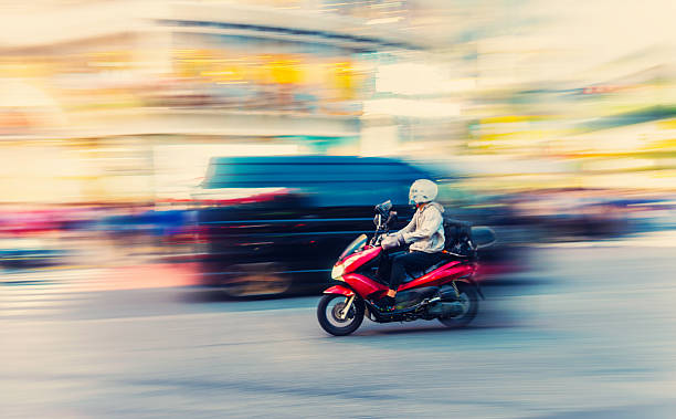 istock Red motor scooter speeding through city at dusk 2218985060