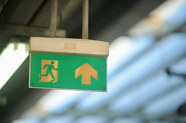 istock Illuminated emergency exit sign with running man icon and arrow. 2218985793