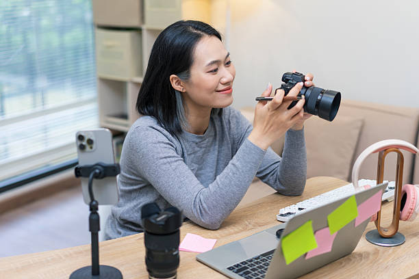 istock Woman with camera enjoying creative work at home office desk with various equipment and natural light from window 2218991021