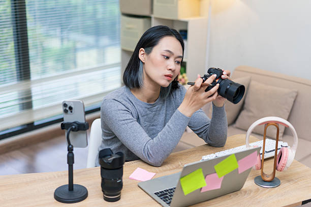 istock Young woman adjusting camera settings while working at a desk in a modern office space with natural light 2218991024