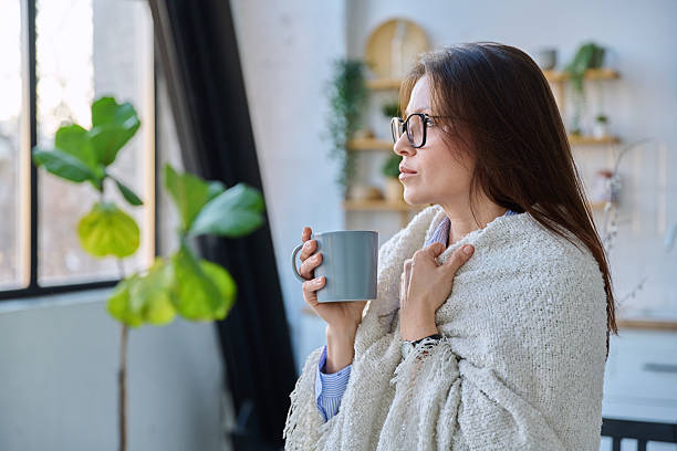 istock Relaxed middle aged woman with mug under blanket in home interior 2218995598