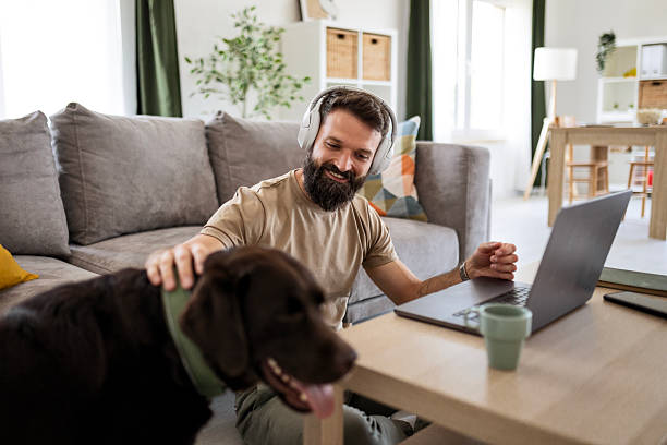 istock Man Working, Listening, and Playing with Dog 2218998120