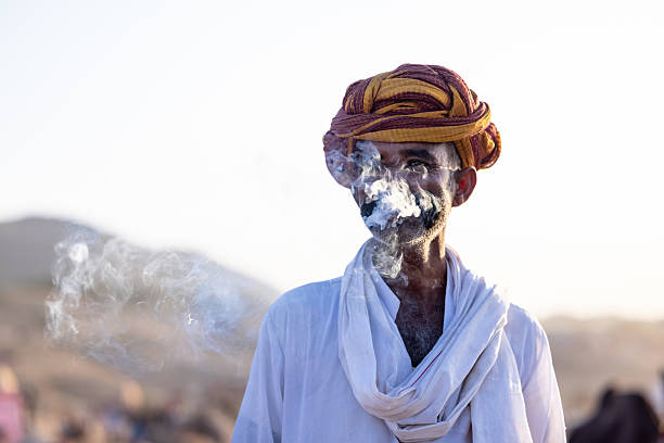 Pushkar, Rajasthan, India - November 2024: Portrait of a rajasthani male in traditional white clothes with colourful turban at desert fair ground during the pushkar camel fair to trade camels.