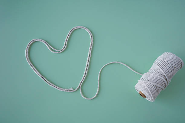 A white cotton rope gently shaped into a heart on a mint green backdrop. The minimalist style and soft tones convey warmth, tenderness, and human connection — suitable for Valentine's designs, wellness brands, or lifestyle content.