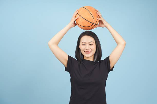 istock Young woman happily poses with basketball in bright studio against blue backdrop 2219006384