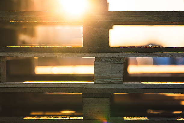 istock sunlight filtering through stacked wooden pallets.. 2219011455