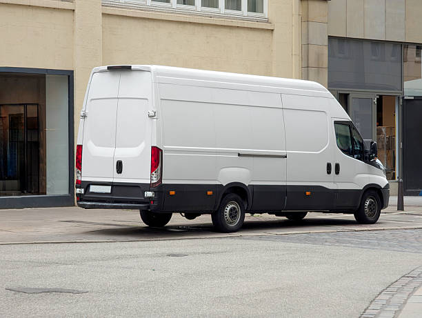 istock Long white delivery van in city – side view with blank space for advertisement 2219011680