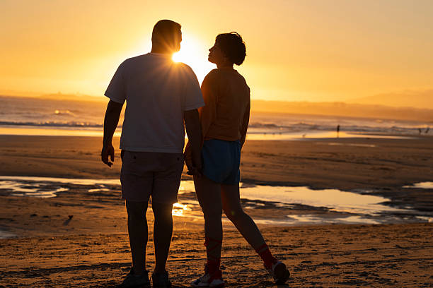 istock Couple holding hands and watching golden sunset at beach 2219012366