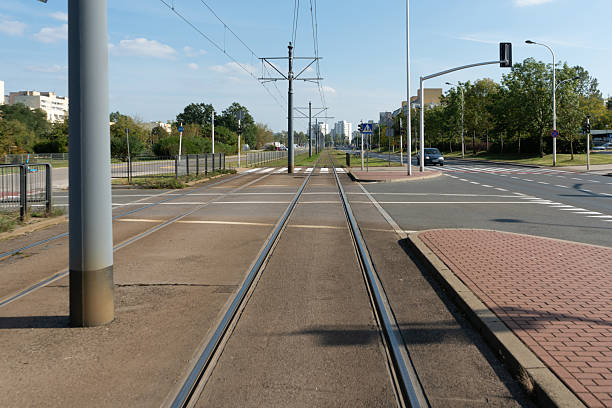 Empty tram tracks with a vanishing point perspective stretch through a modern city. This light rail infrastructure represents public transportation, urban mobility, and the journey ahead.
