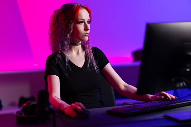 istock Focused female gamer interacting with computer in vibrant neon-lit gaming space 2219013828