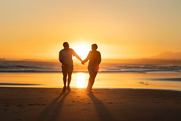 istock Couple walking on beach at sunset holding hands 2219017167