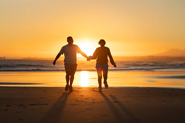 istock Couple running on the beach at sunset holding hands 2219017334