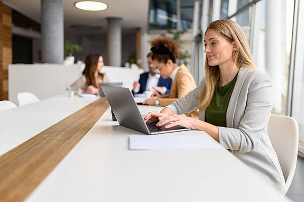 istock Confident female professional analyzing report over laptop while working with colleagues in the meeting room 2219019752