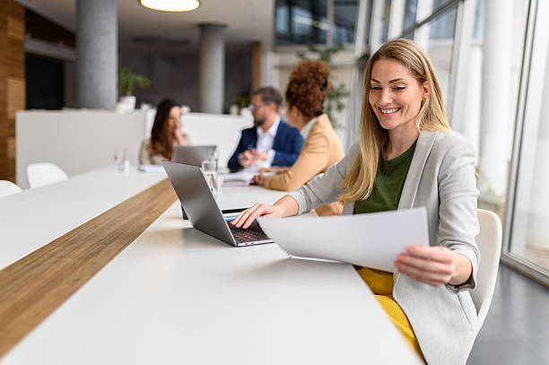 istock Female lawyer analyzing documents and using laptop while working in conference room with colleagues in the background 2219019757