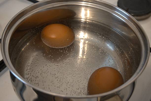 istock Two brown chicken eggs in the water in the cooking pan. 2219020078