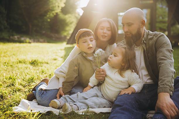 istock Family blowing dandelions in a park during sunset 2219021080