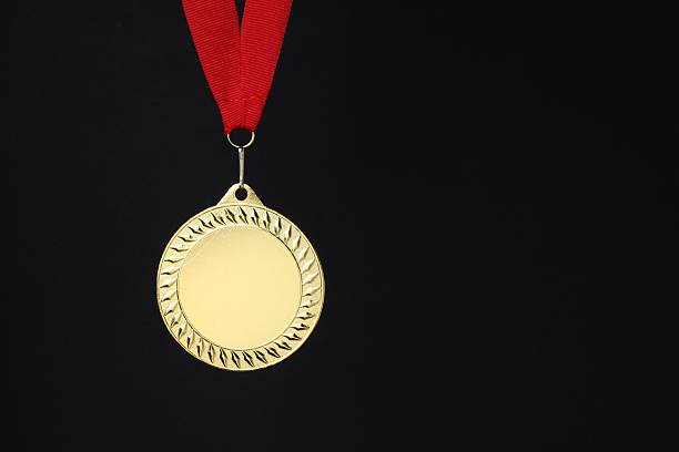 Golden medal with red ribbon on black background, space for text