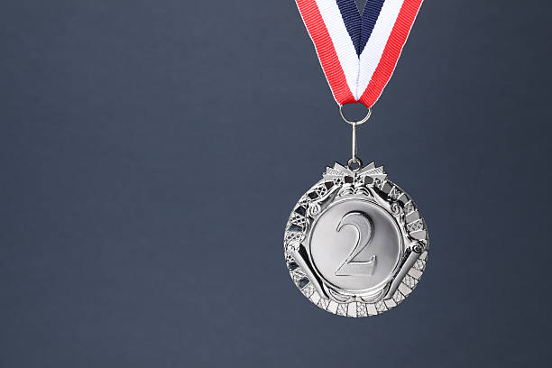 Silver medal with striped ribbon on grey background, space for text
