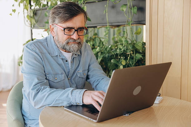 istock Senior businessman working on laptop in modern office with plants 2219023087