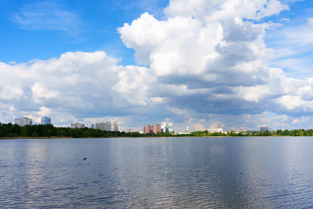 Wide-angle shot capturing the Kyiv skyline and peaceful waters under a partly cloudy sky during the day.