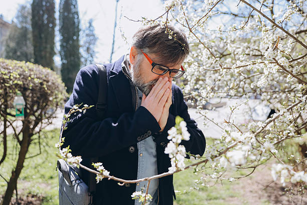 istock Senior man suffering from pollen allergy in spring next to blooming tree 2219023767
