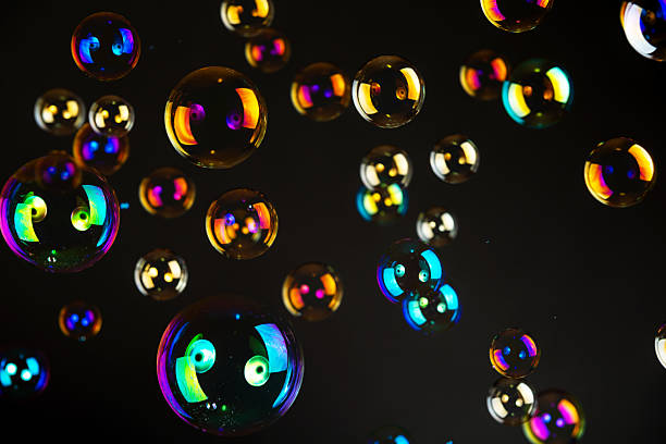 istock Iridescent soap bubbles floating against a black background. Vivid rainbow reflections, abstract and dreamy atmosphere. 2219025228