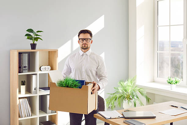 istock Young male office worker who quits or gets fired packs his stuff and leaves the workplace 2219027918